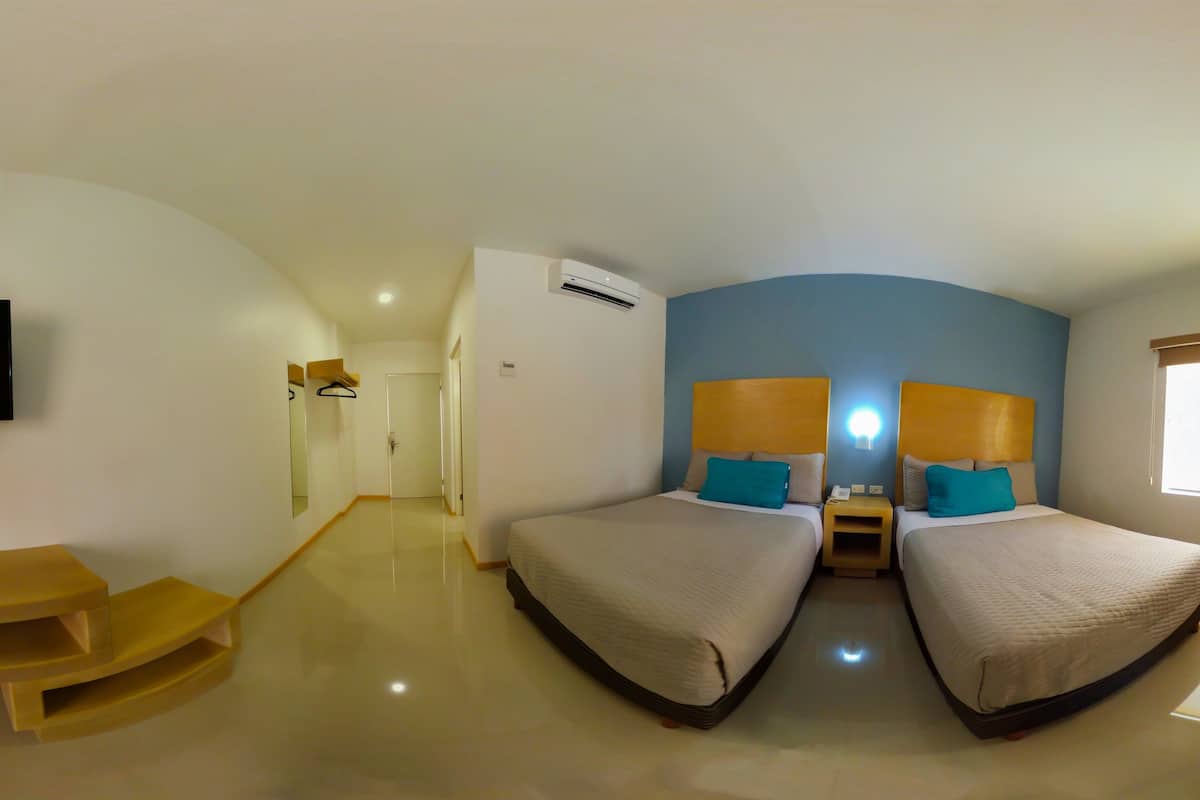 A hotel room with two beds, a TV, an air conditioning unit, and a window with a view.