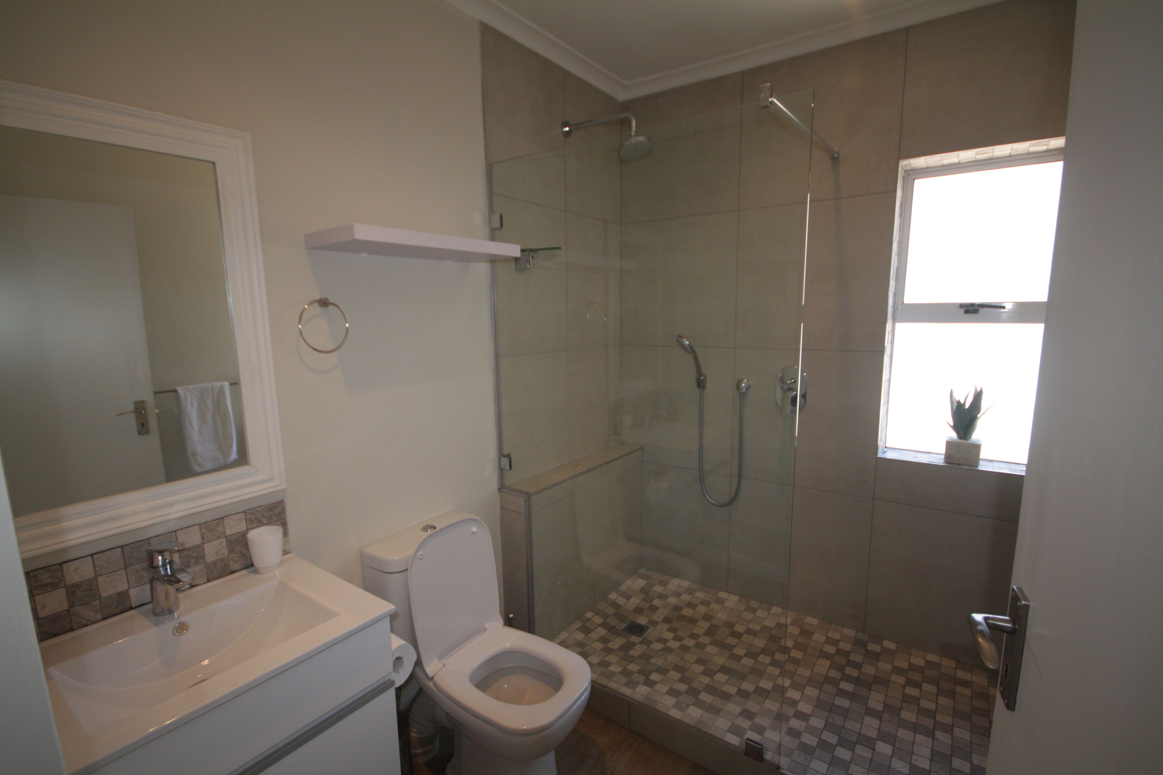 A bathroom with a toilet, sink, and shower area.