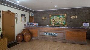 A reception area with a reception desk, a clock, and a sign indicating a restroom. - Reddoorz @ Cemara Beach Sunrise (Denpasar)