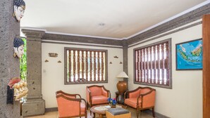 A room with traditional decor, including a wooden chair, a small table, and a decorative lamp. - Reddoorz @ Cemara Beach Sunrise (Denpasar)