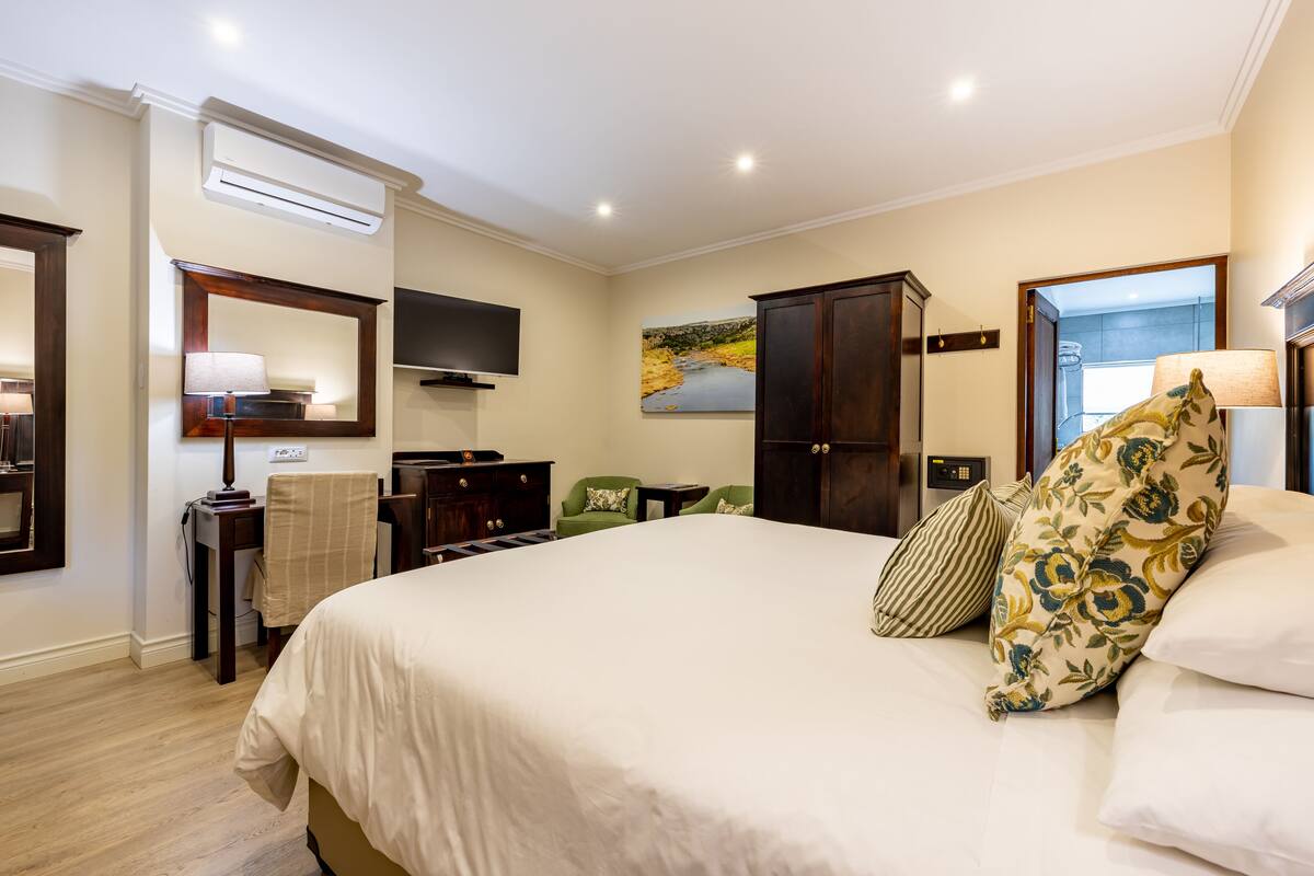 Une chambre d’hôtel avec un grand lit, un téléviseur à écran plat, un tableau au mur et un bureau avec une lampe.