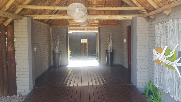 Un porticato in legno con tetto di paglia che conduce a una porta.