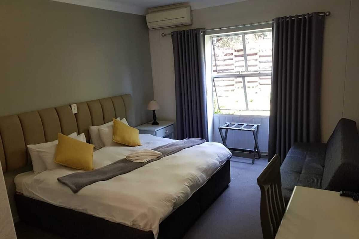 Une chambre d’hôtel avec un grand lit, un bureau, une chaise et une fenêtre avec des rideaux.