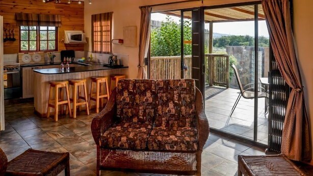 En hyggelig indretning med sofa, barområde og skydedør til en udendørs terrasse.