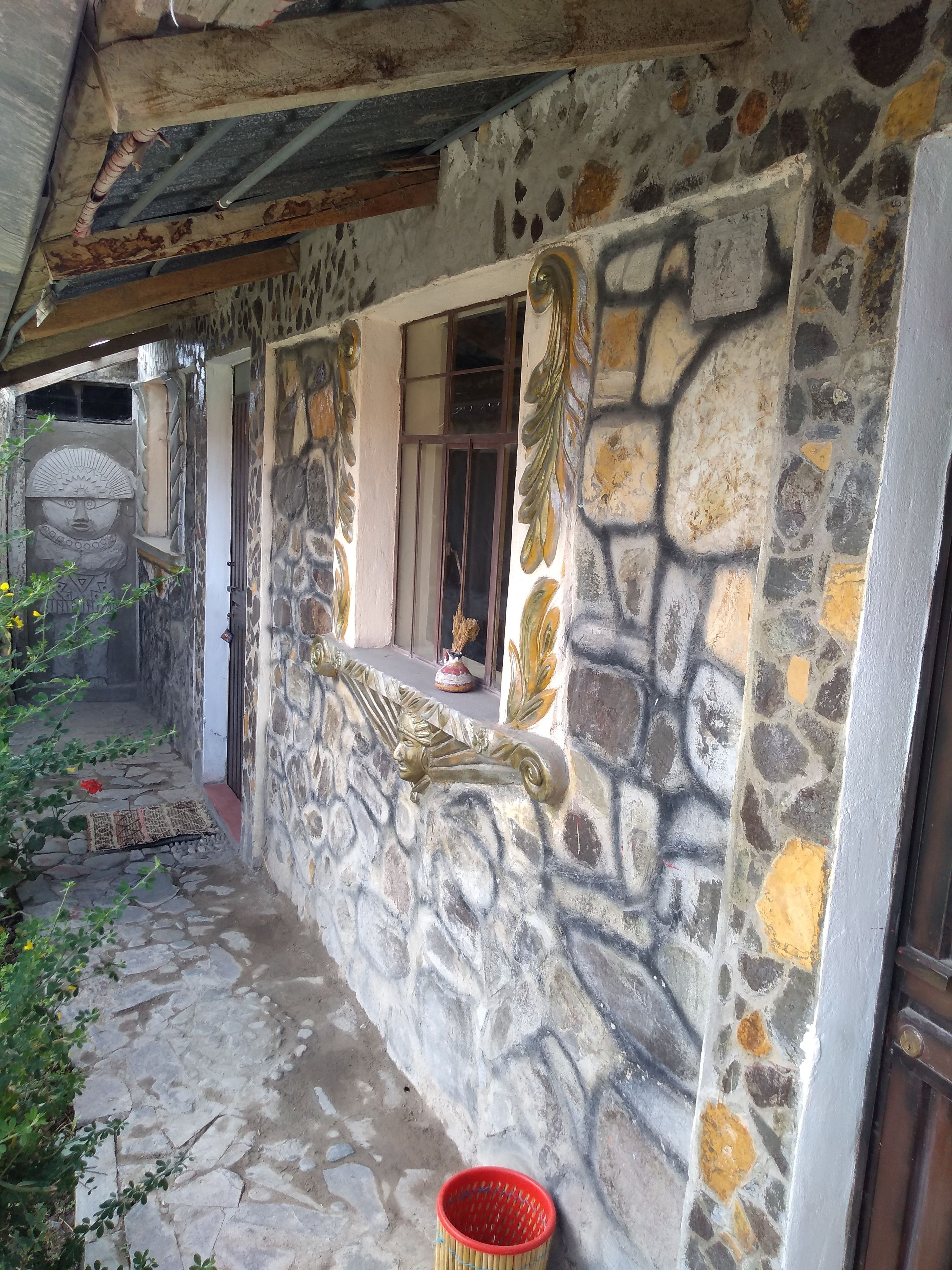 A stone-walled building with a window and a decorative metal crest.