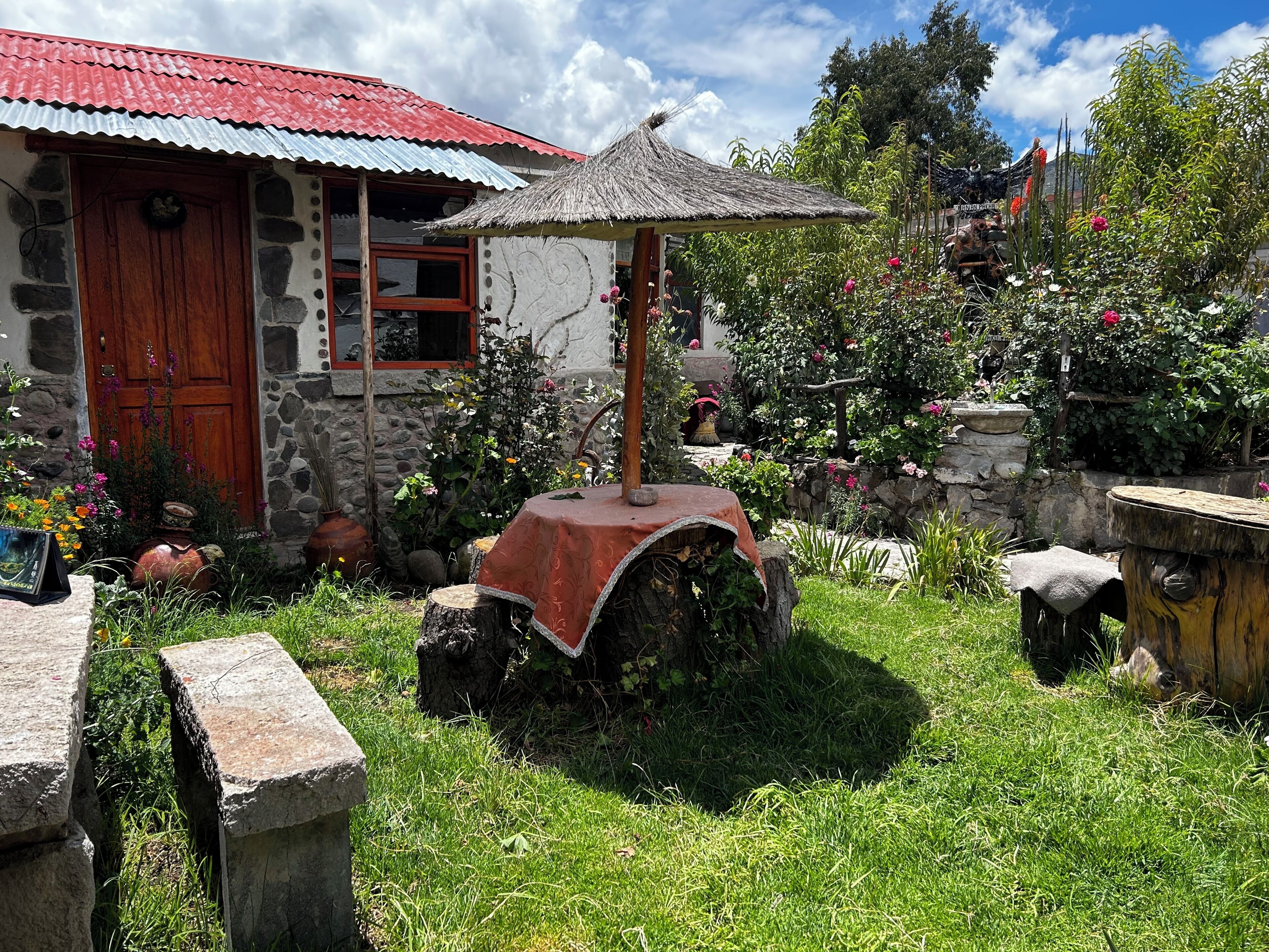 Un edificio rústico de piedra con techo rojo, una puerta de madera y un toldo de paja.