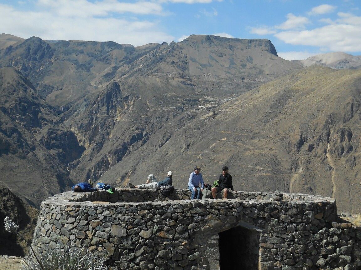 A stone structure with a small opening, surrounded by mountainous terrain.