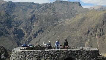 A stone structure with a small opening, surrounded by mountainous terrain.