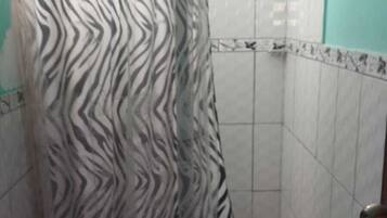 Un baño con cortina de ducha a rayas de cebra, inodoro blanco y paredes con azulejos.