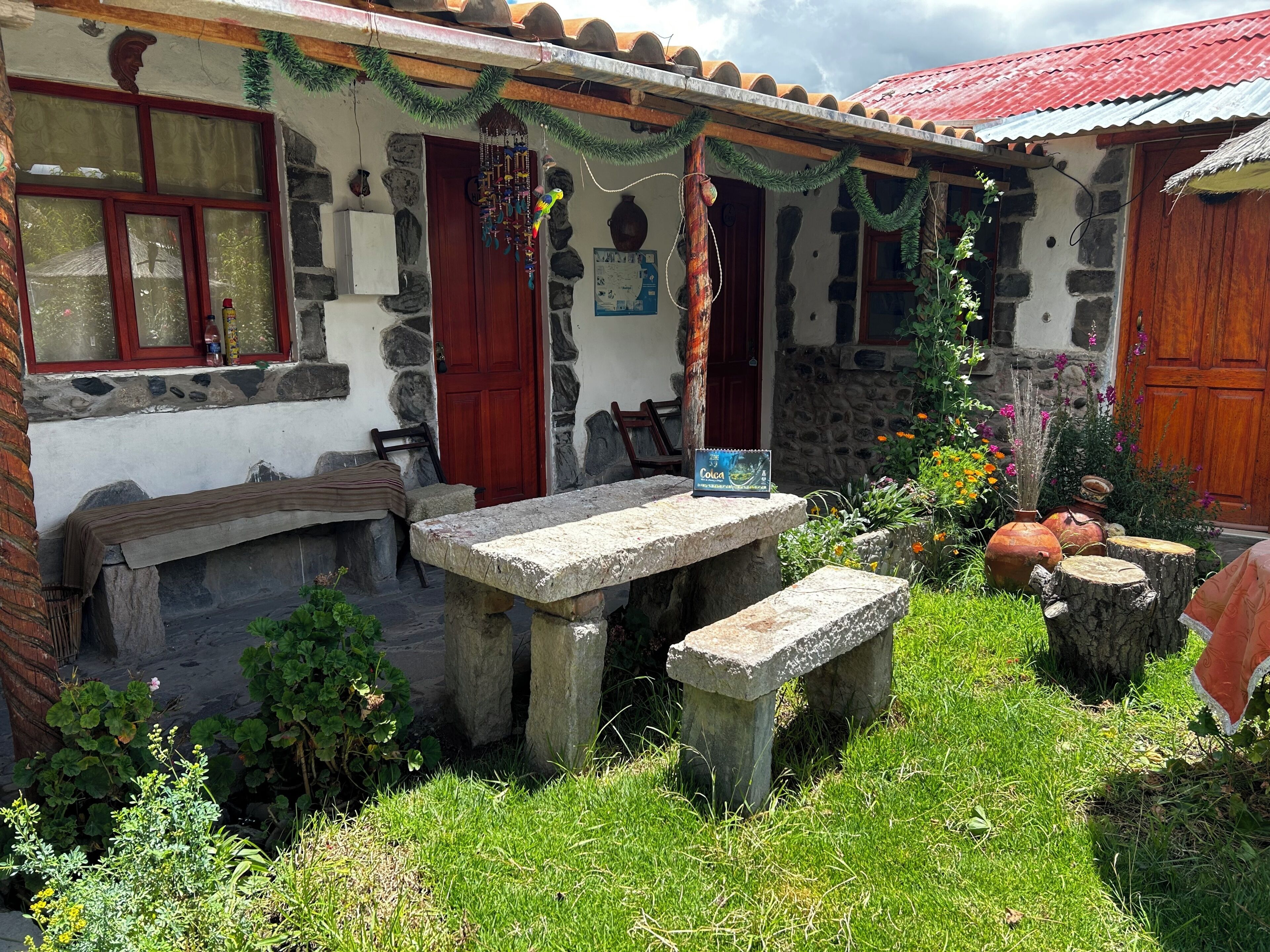 A rustic stone house with a porch, a bench, and a table.
