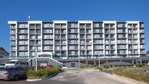 A multi-story residential building with balconies, a parking area, and a clear sky. - Hillside Heights 503 by CTHA (Cape Town)