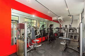 A gym with exercise equipment, a mirrored wall, and a red accent wall.