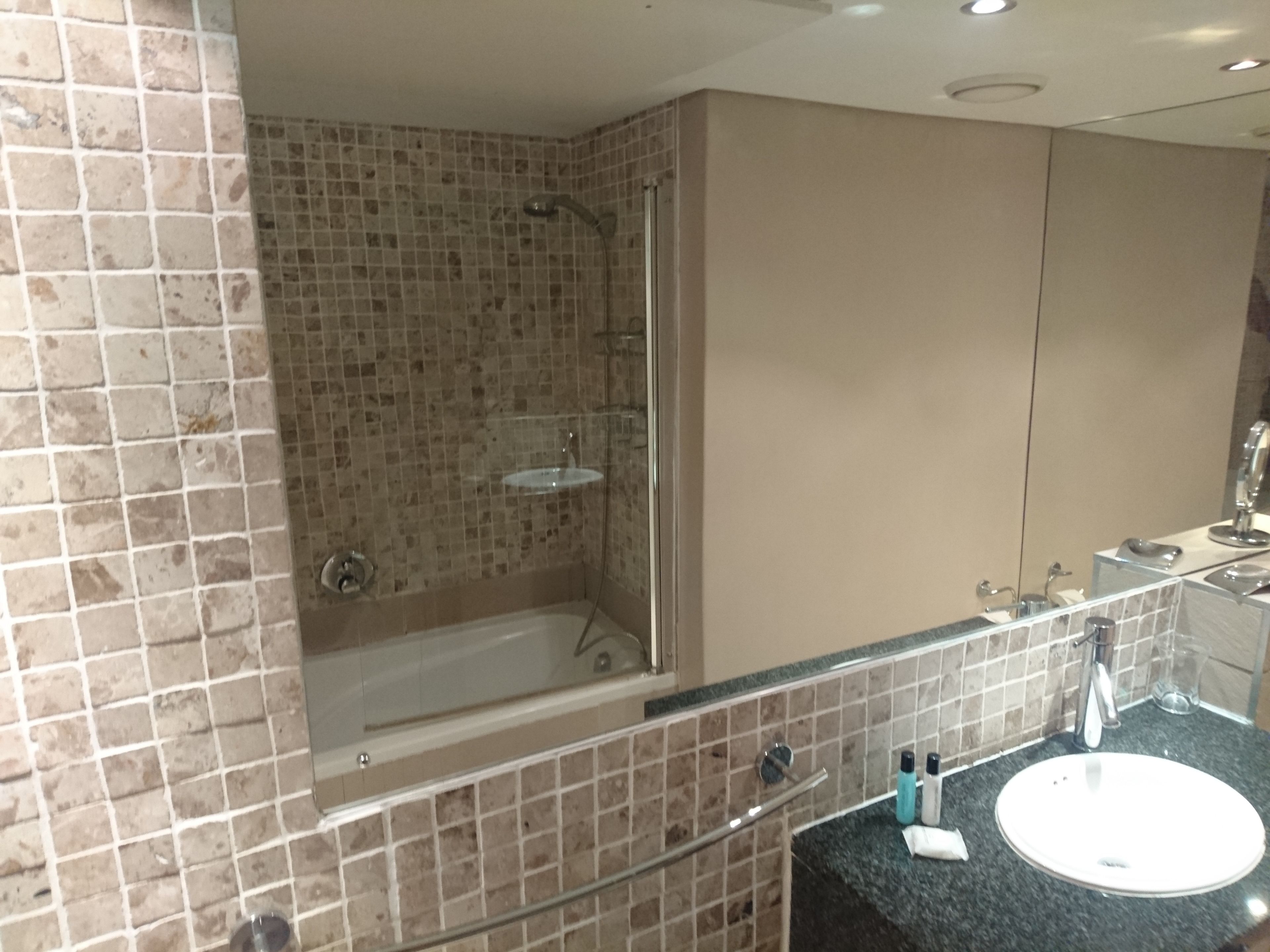 A bathroom with a bathtub, a sink, and a mirror.