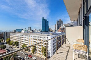 A high-rise building with a balcony overlooking a cityscape, featuring modern architecture and clear skies.