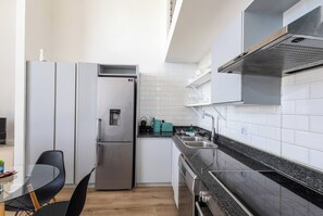 A compact kitchen with a refrigerator, sink, and stove.