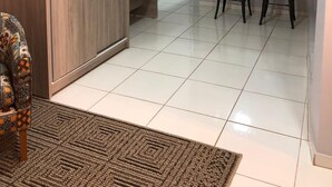 Una cocina moderna con refrigerador, dos taburetes de bar y luces colgantes.
