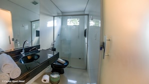 Un baño moderno con cabina de ducha de vidrio, un lavamanos negro y un inodoro.