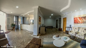 Un vestíbulo de hotel con mostrador de recepción, zona de estar y un cuadro grande en la pared.