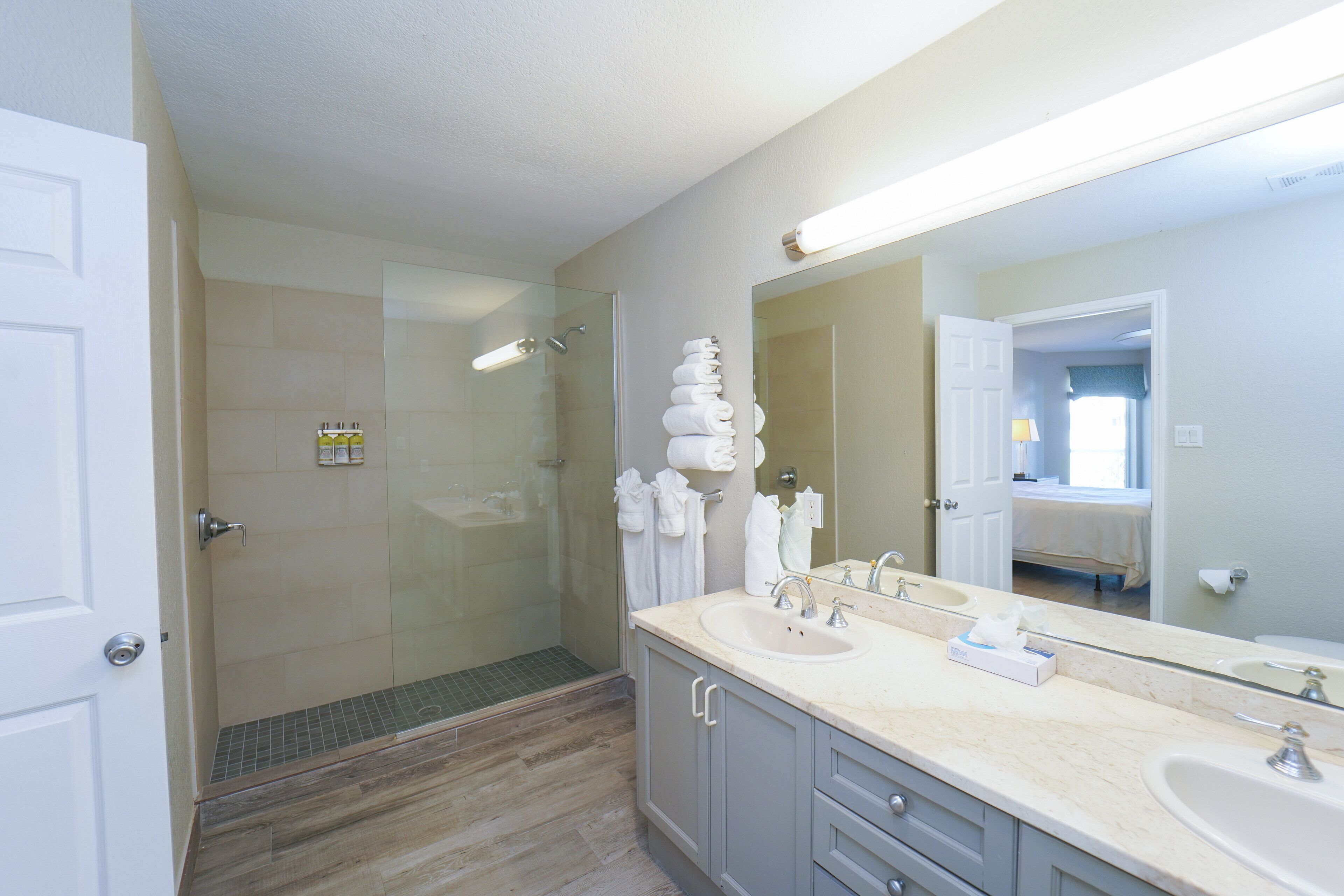 A modern bathroom with a glass-enclosed shower, a large mirror, and a vanity with a sink and countertop.