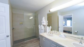 A modern bathroom with a glass-enclosed shower, a large mirror, and a vanity with a sink and countertop.