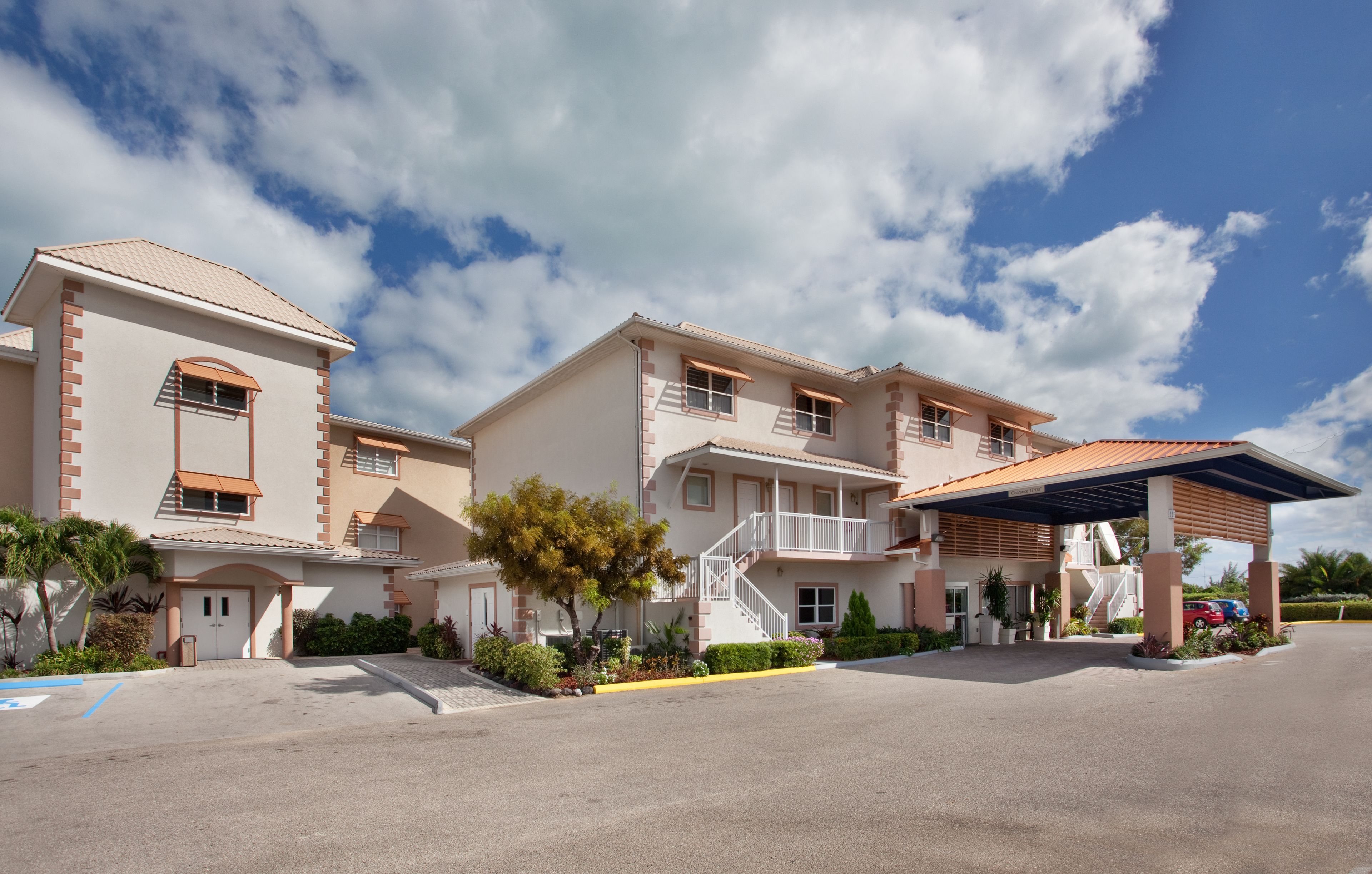 A multi-story hotel with a covered parking area, a staircase, and a small outdoor seating area.