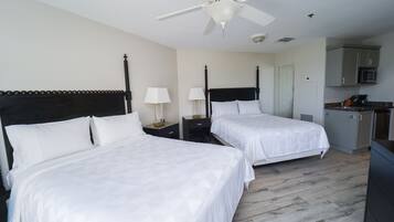 Une chambre d’hôtel avec deux lits, un ventilateur de plafond, un four à micro-ondes et une kitchenette.