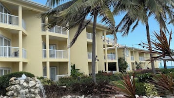 Un resort con piscina cristalina, palmeras y un edificio con balcones.