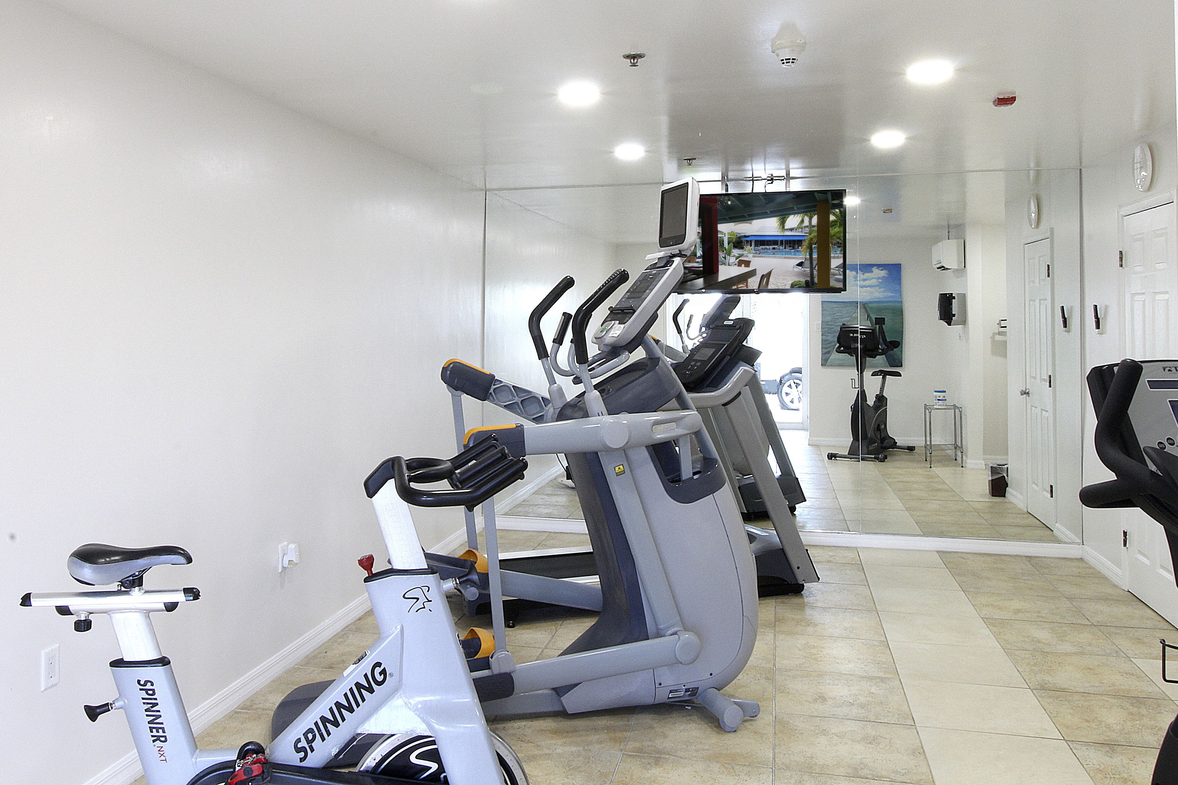 Een sportschool thuis met twee hometrainers en een elliptische machine.