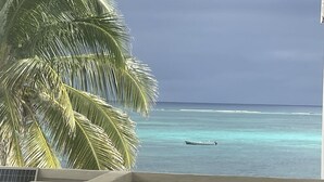 A view of a beach with a boat in the water, palm trees, and a clear sky. - Spindrift Hotel (San Pedro)