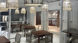 A spacious restaurant with high ceilings, exposed beams, and natural light. Tables and chairs are arranged for dining. - Spindrift Hotel (San Pedro)