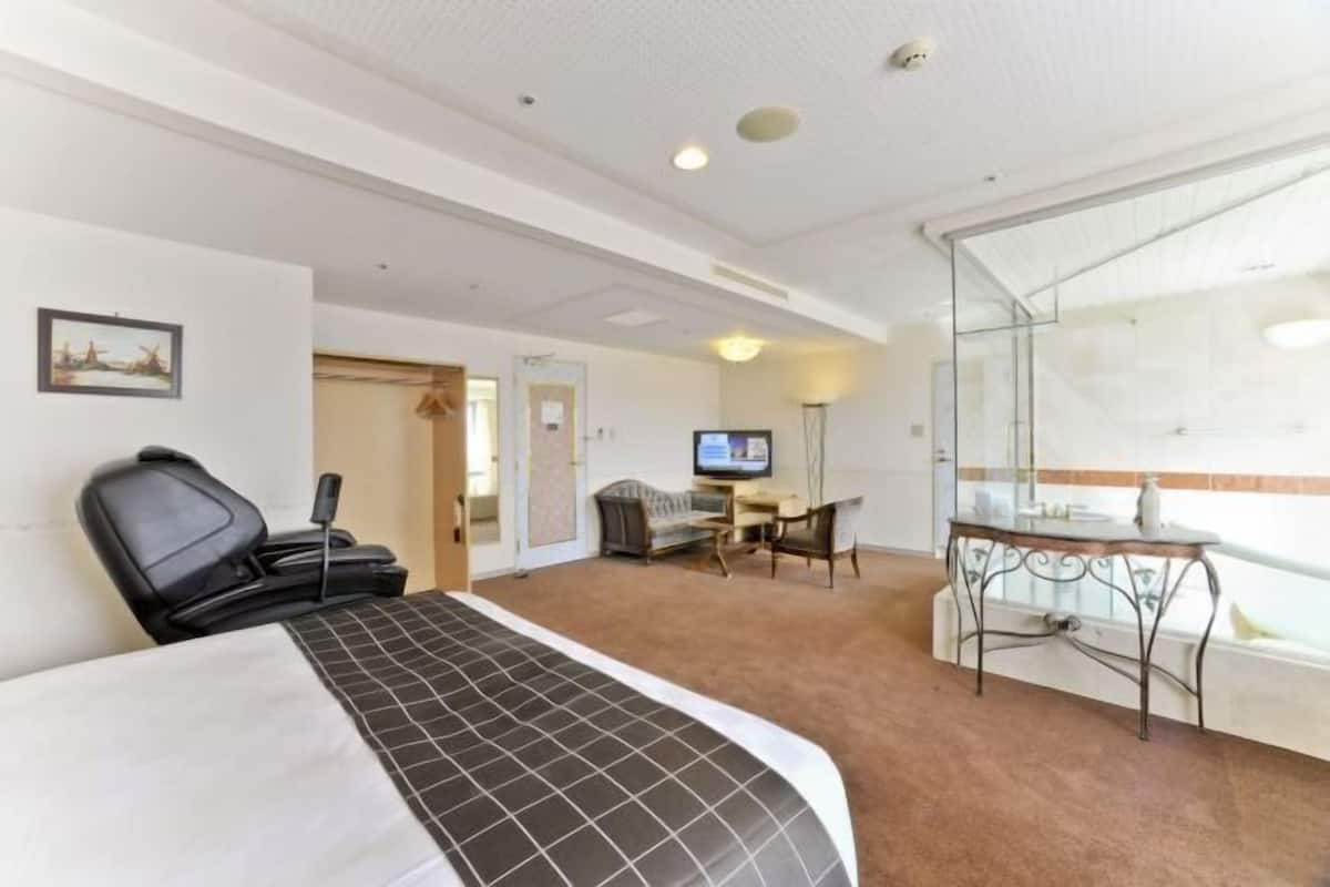 Ein Hotelzimmer mit Bett, Schreibtisch, Stuhl, Fernseher und einem großen Fenster.