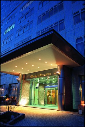 L’entrée d’un hôtel, avec une façade moderne, une entrée bien visible et une enseigne indiquant le nom de l’hôtel.