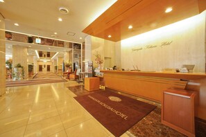 Un hall d'accueil d'hôtel avec un sol en marbre, un comptoir de réception et une enseigne indiquant « Yamagoza Kokusai Hotel ».