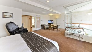 Hotelkamer met een bed, een bureau met een computer, een stoel en een douchecabine.