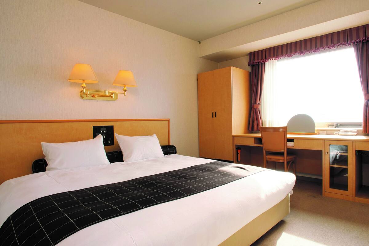 Une chambre d’hôtel avec un grand lit, un bureau et une chaise.