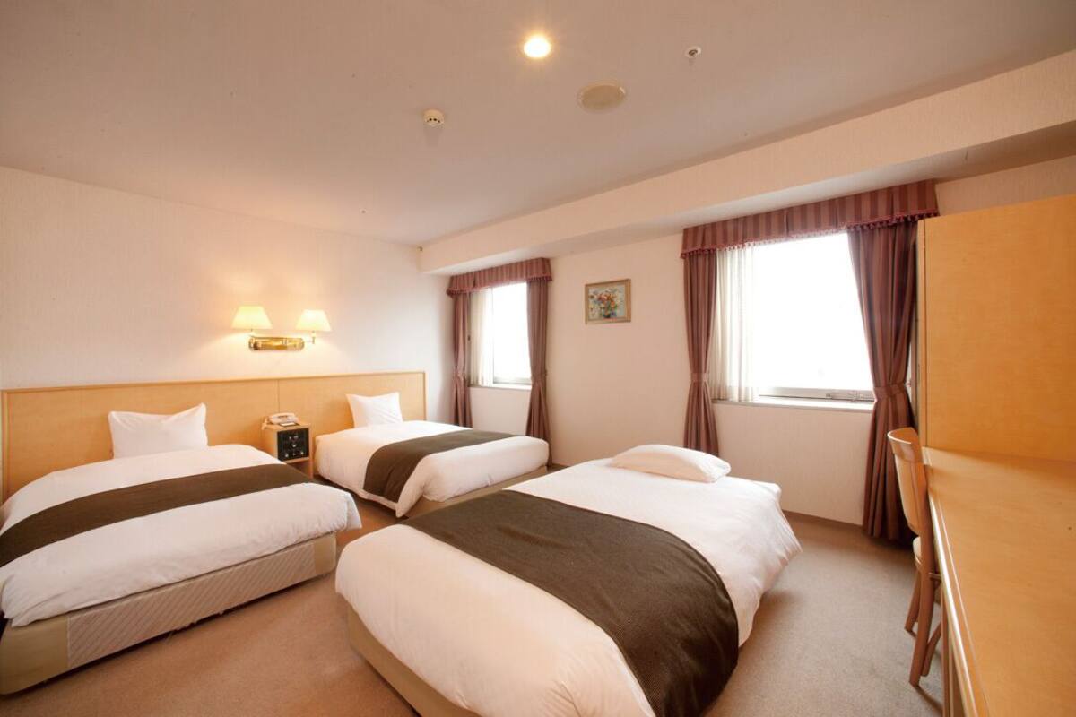 Une chambre d’hôtel avec deux lits, un bureau et une table de chevet avec une lampe.