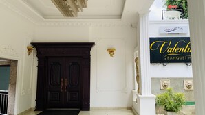 A hotel entrance with a dark wooden door, a chandelier, and a sign for 'Valenti Banquet Hall'. - Hotel Gangaaddara (Kandy)