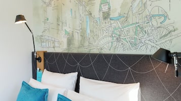 A hotel room with a bed, pillows, a headboard, a wall map, and a lamp.