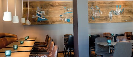 A modern restaurant interior with leather seating, pendant lighting, and large wooden tables.