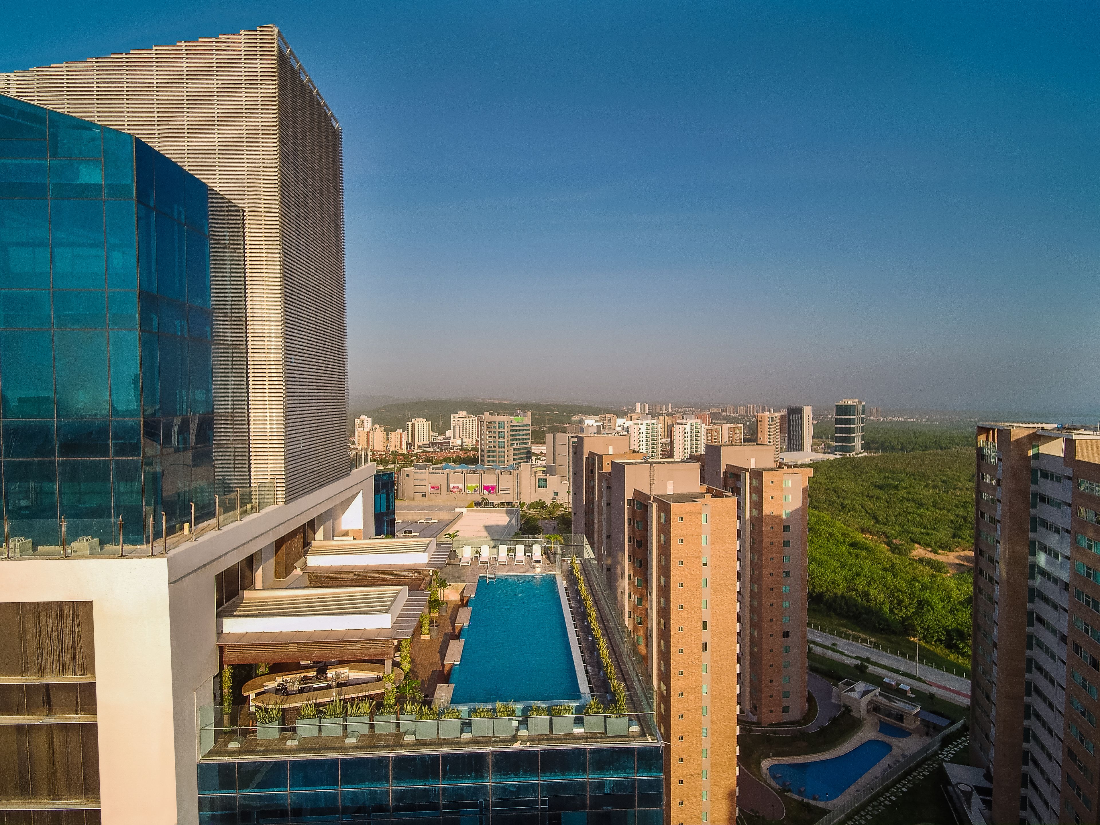 A high-rise building with a rooftop pool and adjacent residential buildings.
