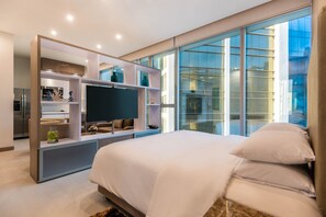 Een moderne slaapkamer met een groot bed, een televisie en een glazen wand.