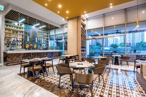 A modern restaurant with a bar area, dining tables, and chairs. - Crowne Plaza Barranquilla by IHG (Barranquilla)