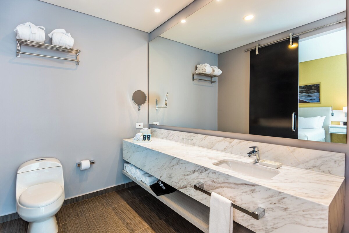Een moderne badkamer met een marmeren wastafel, toilet en handdoekhouder.