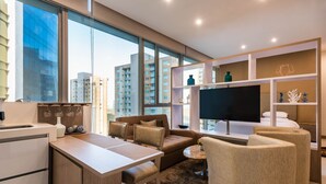 Una sala de estar moderna con un sofá, sillas, un televisor y una zona de cocina.