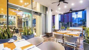 Un restaurant moderne avec une salle à manger intérieure, un mur en verre et une vue sur le paysage urbain.