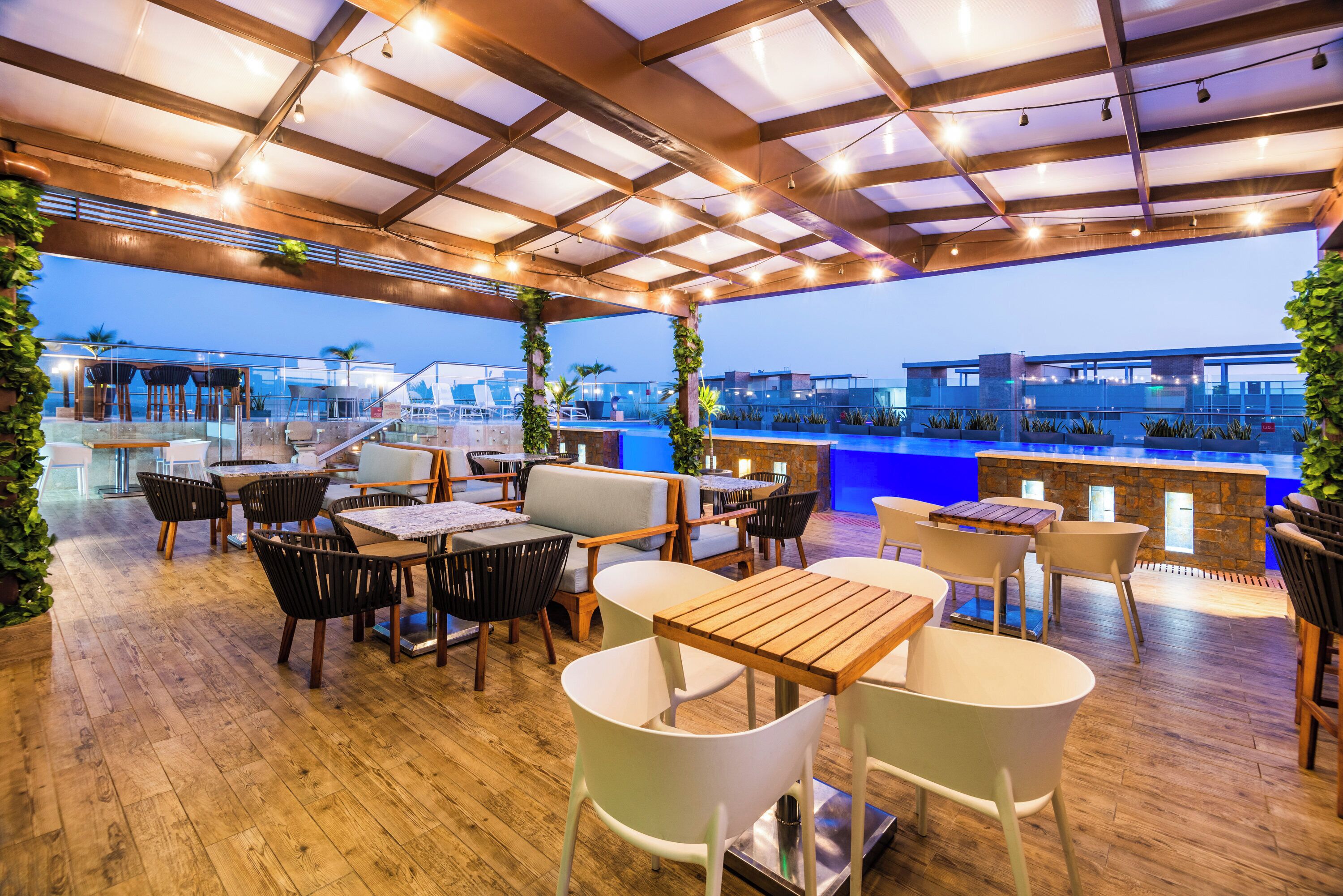 An outdoor seating area with tables and chairs, a pool, and a view of the cityscape.