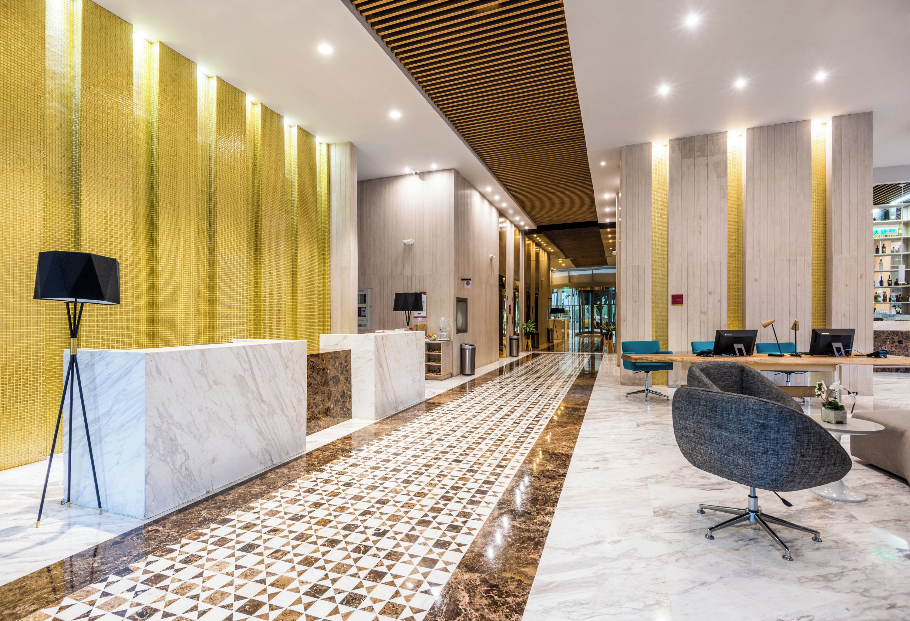 A modern lobby with a reception desk, seating area, and a patterned floor.