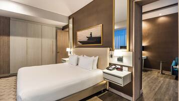 A hotel room with a large bed, bedside tables, a mirror, and a painting on the wall.