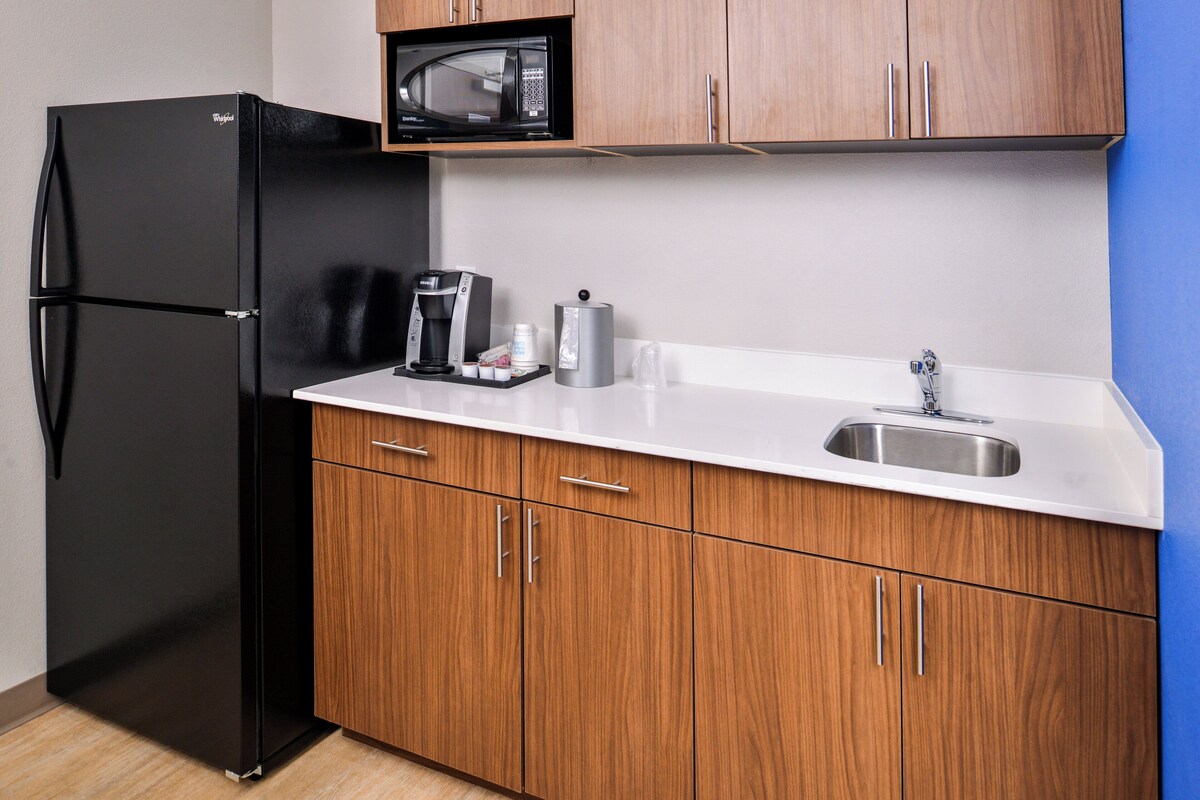 A compact kitchen with a black refrigerator, a microwave, a coffee maker, and a sink.