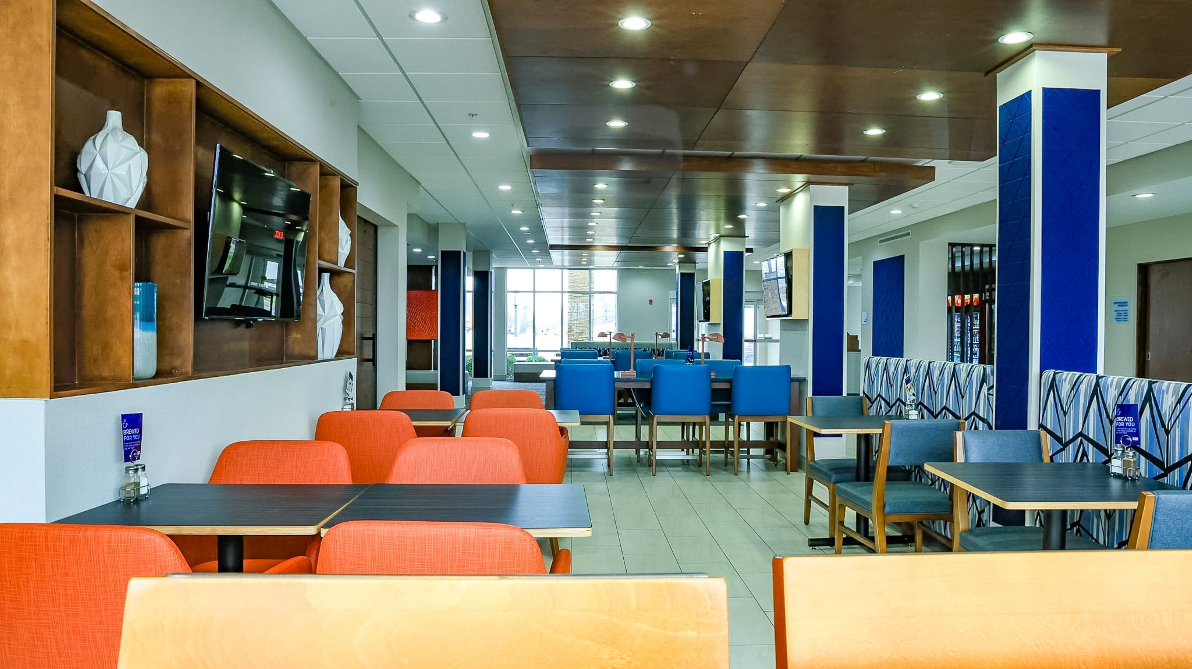 A modern restaurant with multiple seating areas, including tables and booths, and a variety of chairs.